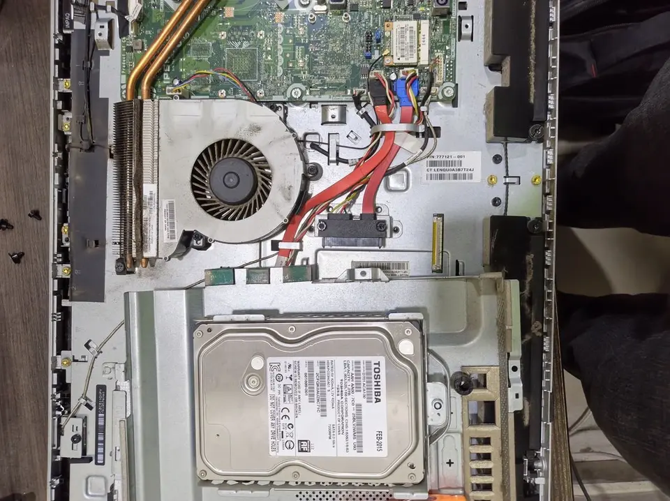 Inside an all-in-one computer showing fan, cables and hard drive